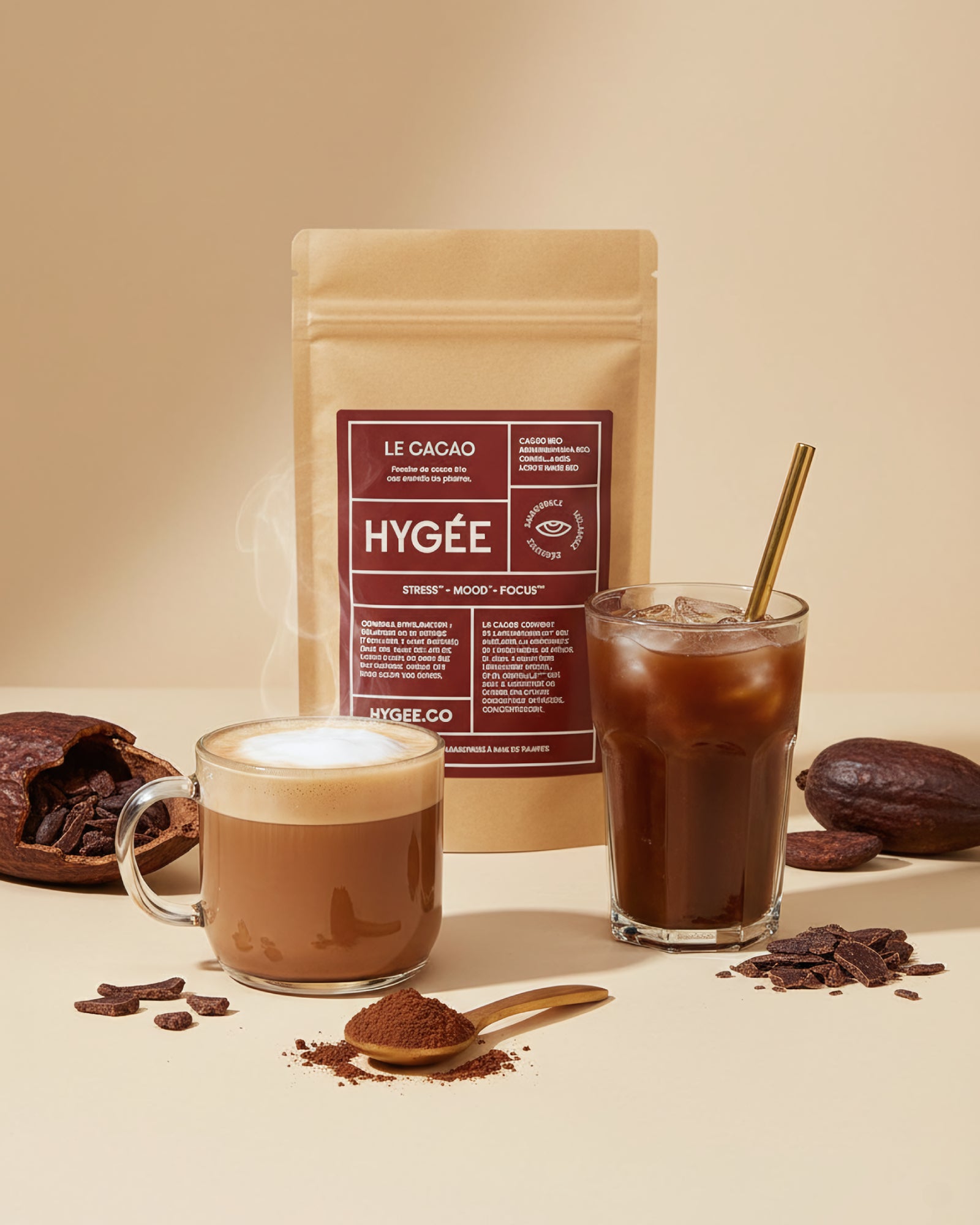 Allnord’s HYGÉE Le Cacao pouch sits behind a steaming hot cacao and an iced cacao with a gold straw, surrounded by spoons of powder and broken chocolate. A bright countertop scene with creamy foam and cool glass reflections.